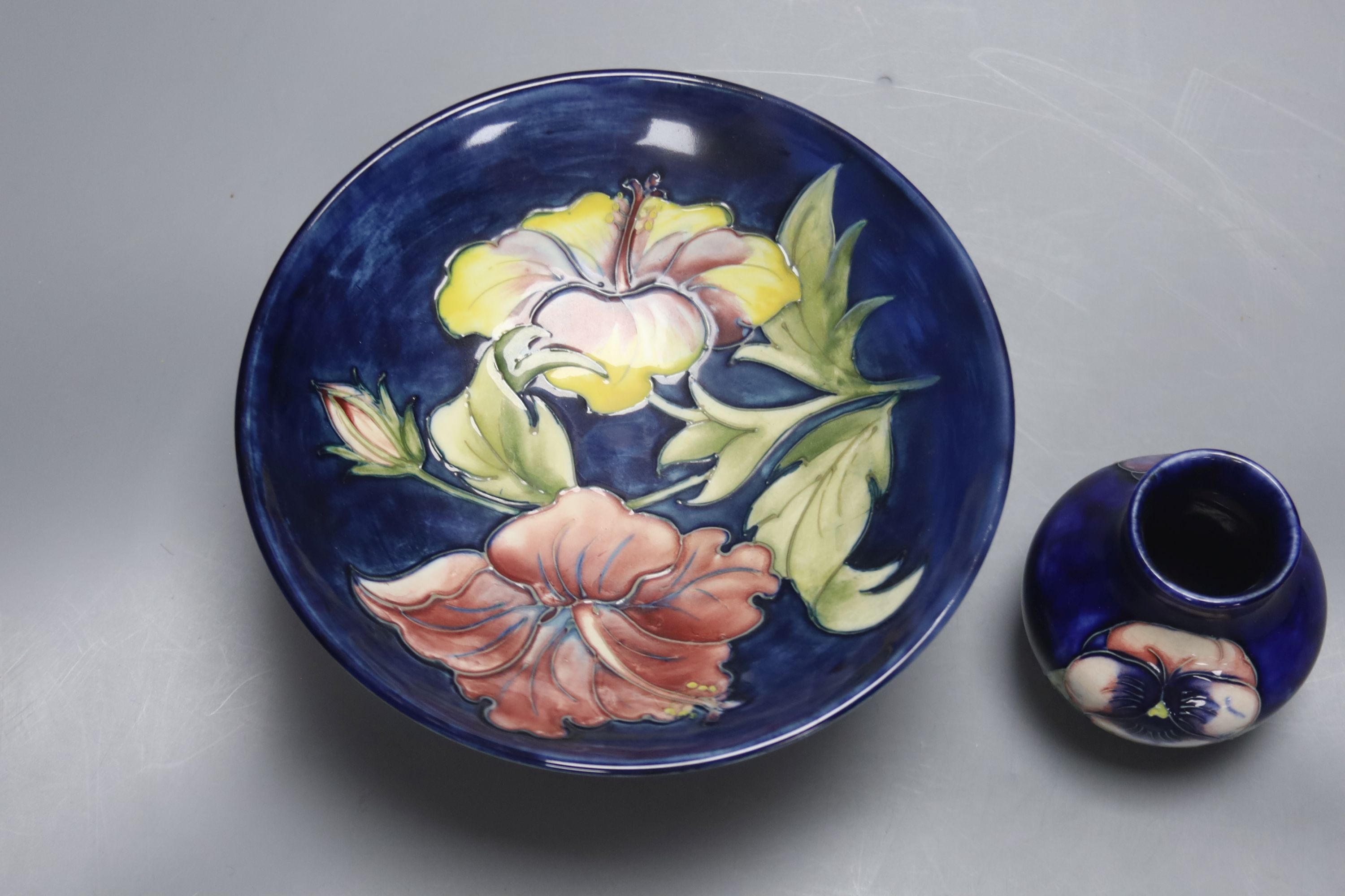 A Moorcroft Hibiscus footed dish, diameter 18cm, and a pansy pattern vase